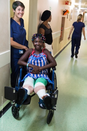 Julienne waits in a wheelchair for the lfit with Bettina Krausert, Ward Nurse.